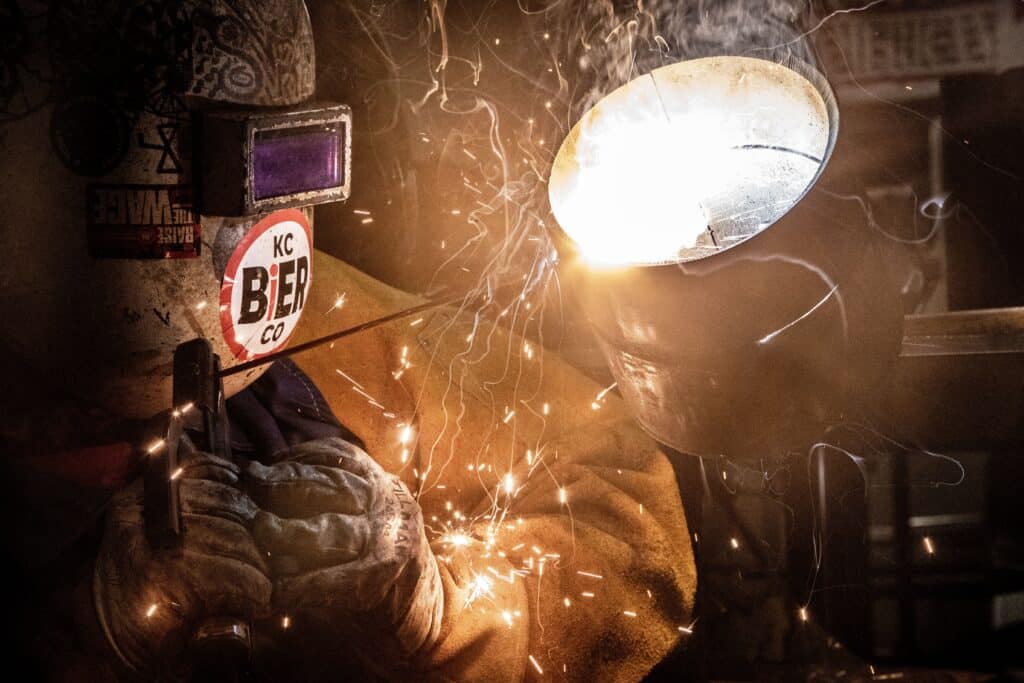 Welder at work with sparks and orange glow illuminating the workspace. Welder at work with sparks and orange glow illuminating the workspace.