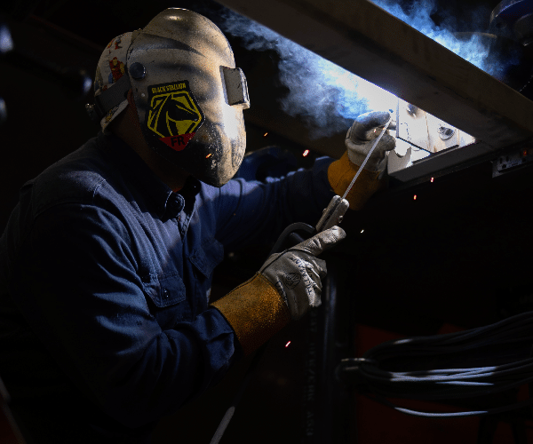 Welder kneeling to perform a weld on a jobsite. Welder kneeling to perform a weld on a jobsite.