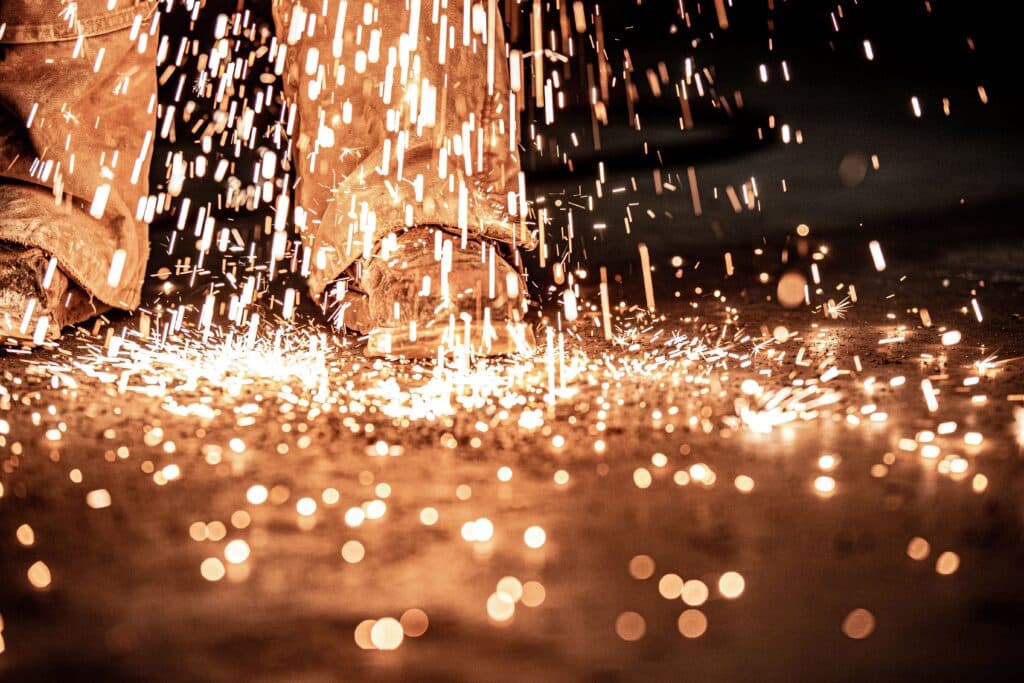 Work boots surrounded by sparks during a welding operation. Work boots surrounded by sparks during a welding operation.